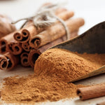 Cinnamon sticks and ground cinnamon in a scoop on a wooden surface